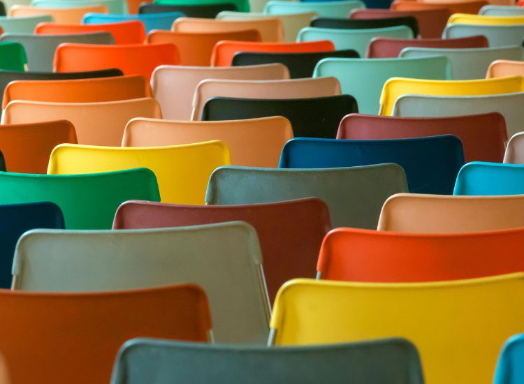 Konferencijske stolice u velikom broju, različite boje sedišta poređane u sali, namenjene intenzivnoj upotrebi i čestoj rotaciji korisnika.