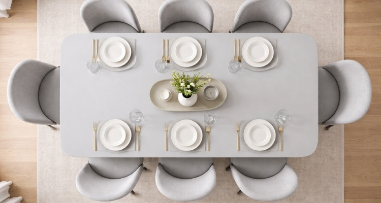 Ptičija perspektiva moderne trpezarije sa sivim stolom i osam tapaciranih stolica, uredno postavljenim posuđem i minimalističkim dekorom na svetlom drvenom podu.