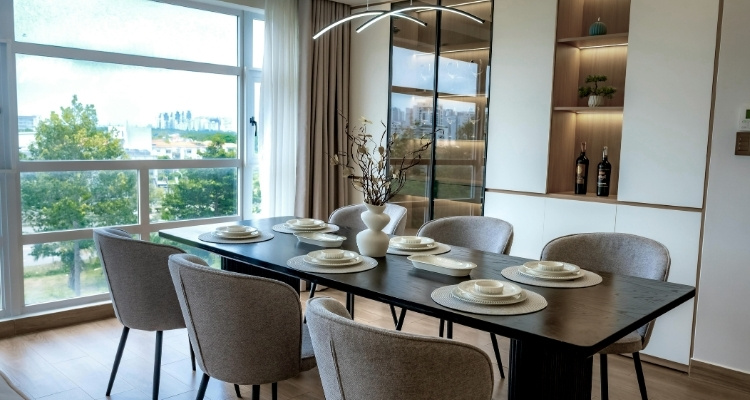 Moderna trpezarija sa pravougaonim tamnim stolom i šest tapaciranih stolica, postavljena pored velikog prozora sa pogledom na zelenilo